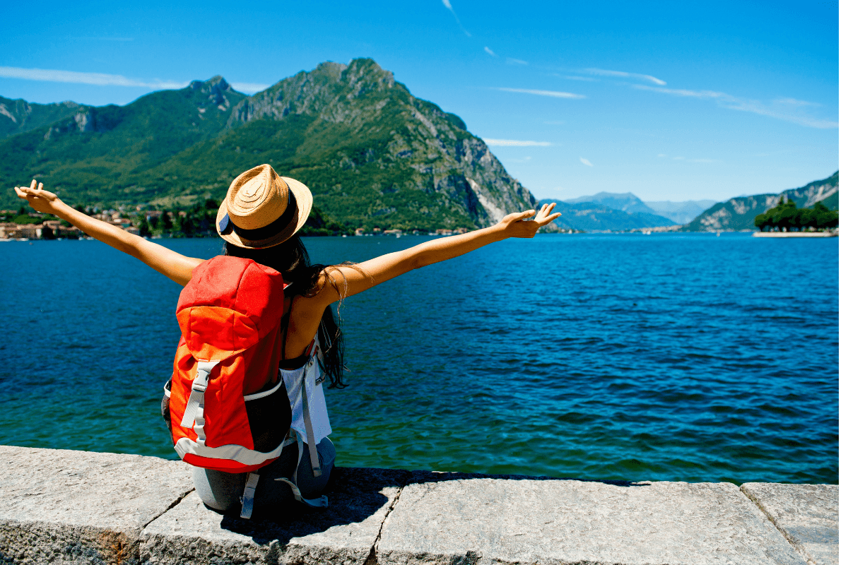 Traveler with backpack celebrating at scenic lake destination representing finding great flight deals