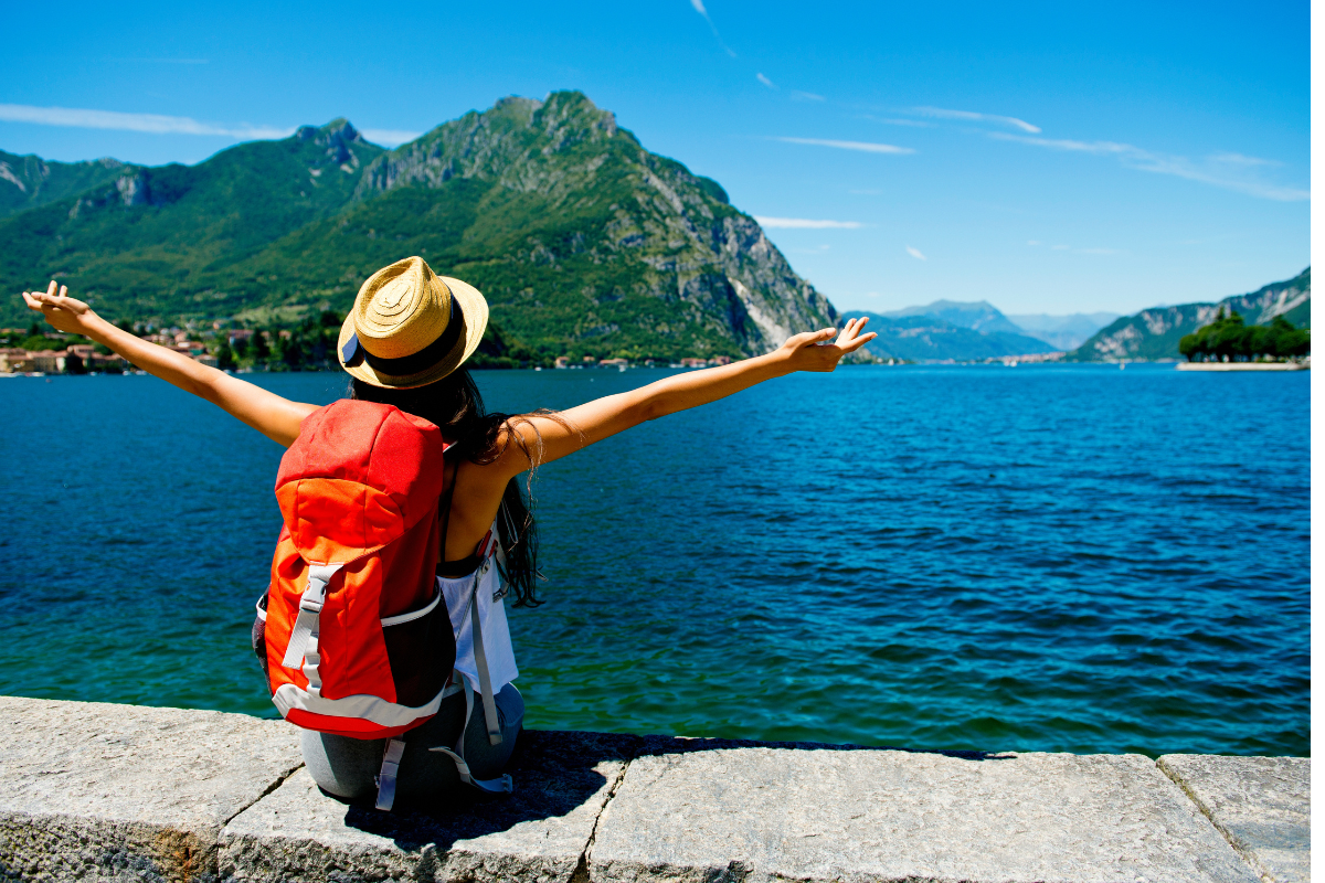 Traveler with backpack celebrating at scenic lake destination representing finding great flight deals